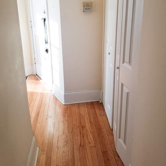 a hallway with a wooden floor and white walls.