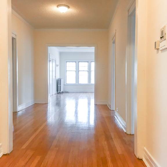 a long hallway with wood floors and white walls.
