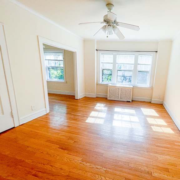 a room with a ceiling fan and wooden floors.