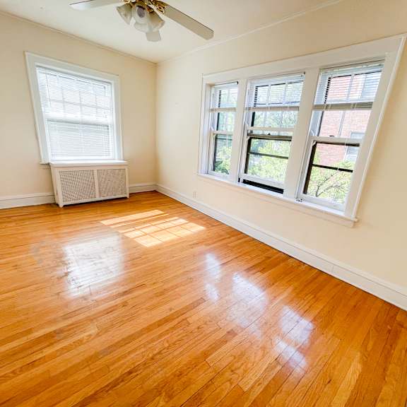 a room with wooden floors and two windows.