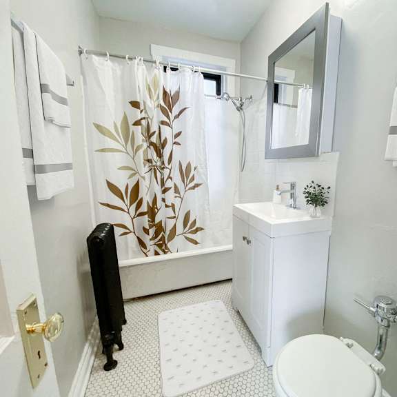 a bathroom with a white toilet, sink, and shower curtain.