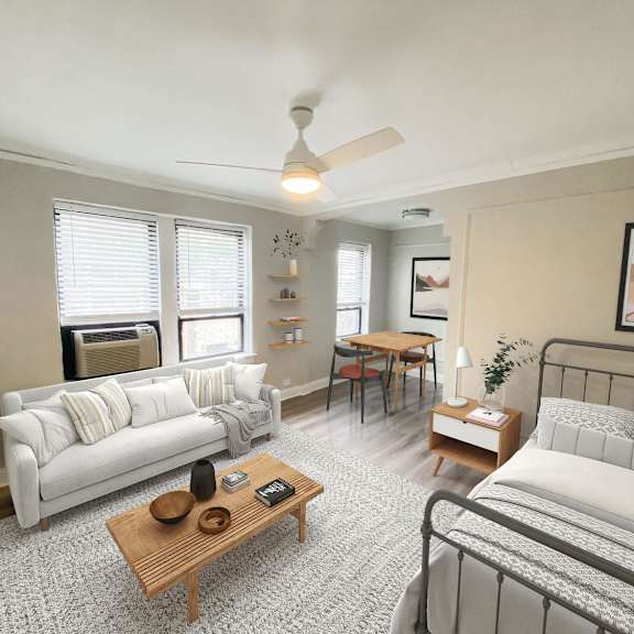 a living room with a white couch, a wooden coffee table, and a bed with a white comforter.