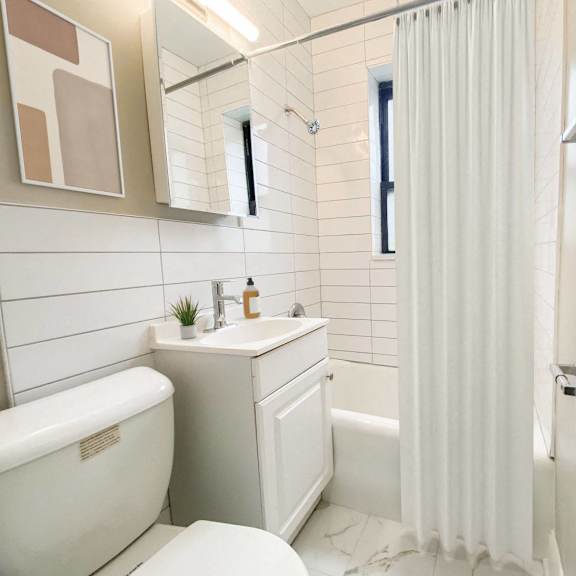 a white bathroom with a tub, sink, and toilet.