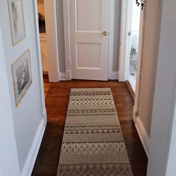 a hallway with a rug on the floor and pictures on the wall.
