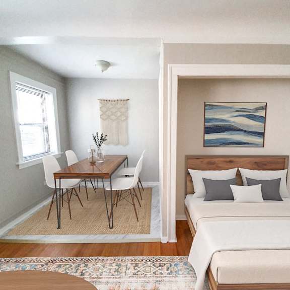 a bedroom with a bed, a table and chairs, and a painting on the wall.