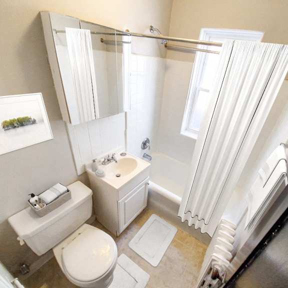 a white bathroom with a toilet, sink, and shower.
