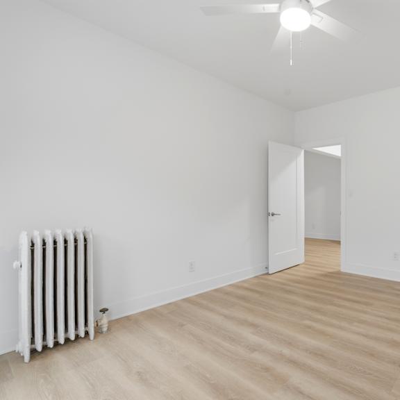 a room with a white wall and a white radiator on the left side.