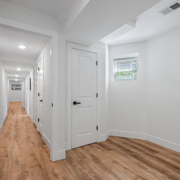a long hallway with white walls and wooden floors.