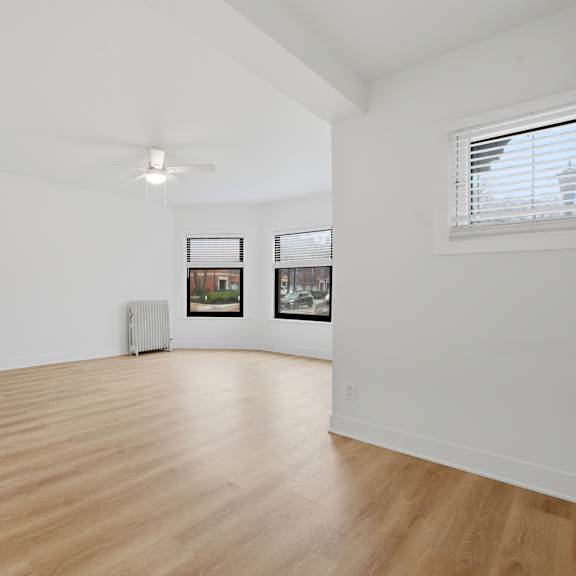 a room with wooden flooring and a window with blinds.