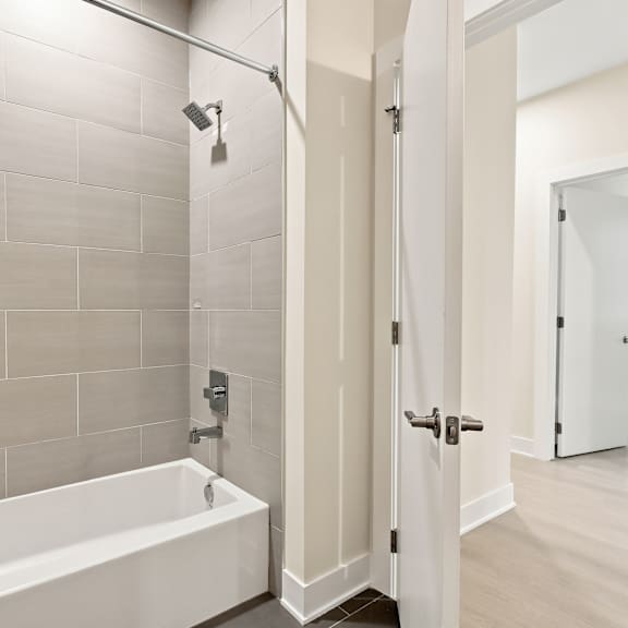 a white bathroom with a tub and a door.