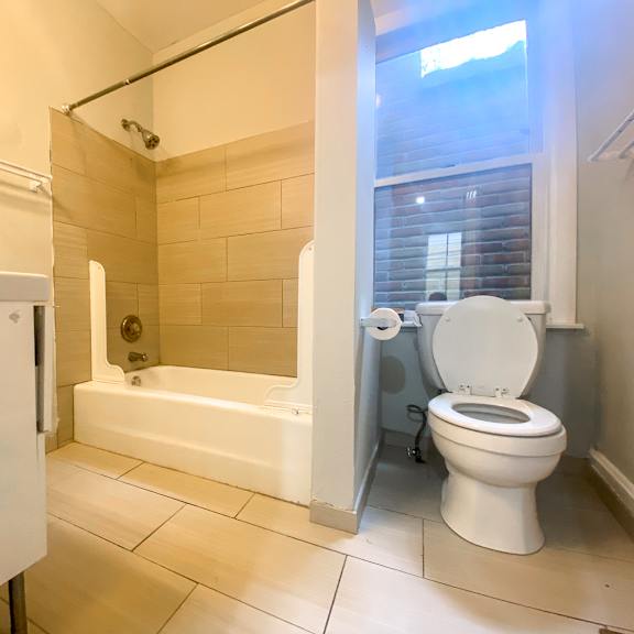 a white toilet is in a bathroom with a tub and a shower.