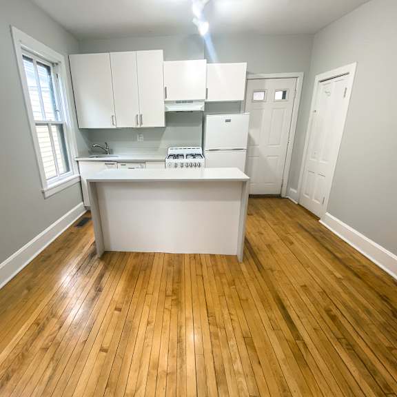 a kitchen with white cabinets and a wooden floor.