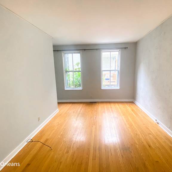 a room with wooden floors and two windows.