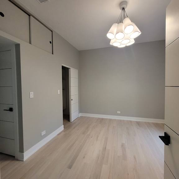 a room with a light hanging from the ceiling and a door to the right.