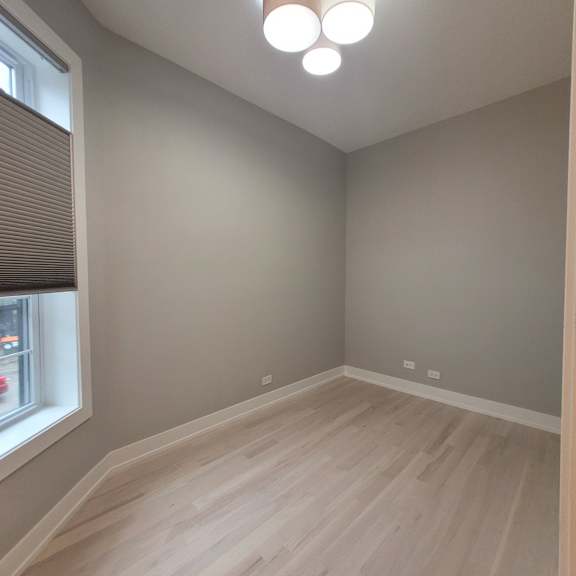 a room with wooden flooring and a window with blinds.