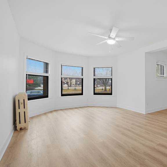 a room with a wooden floor and three windows.