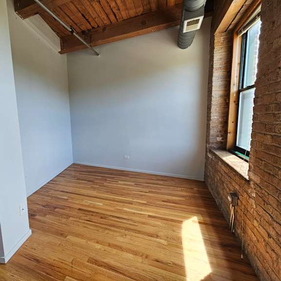an empty room with wood floors and a window