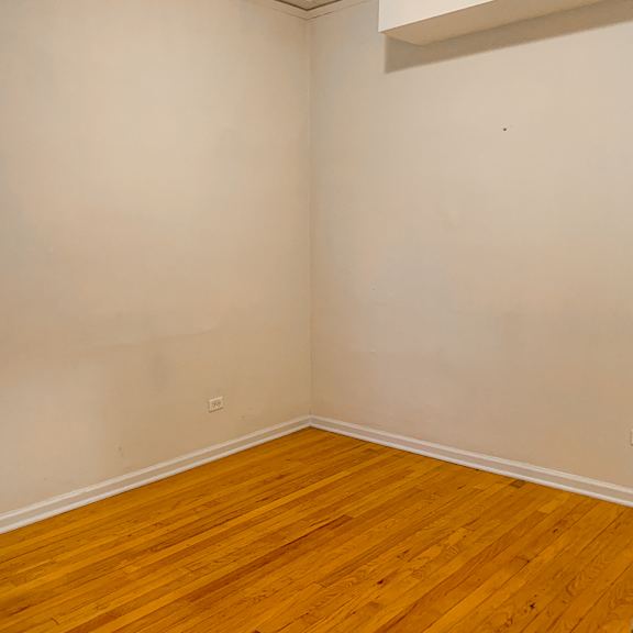 a room with wooden flooring and a window with blinds.
