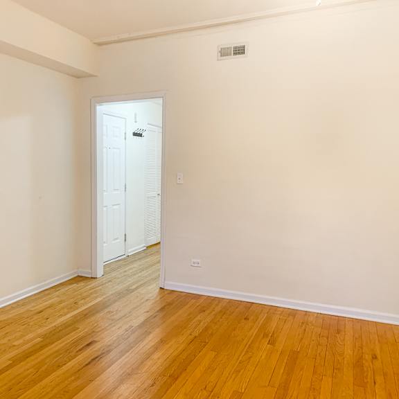 a room with a white door and wooden flooring.