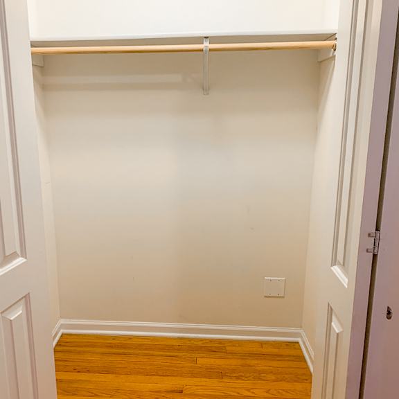 a white wall with a shelf and a wooden floor.