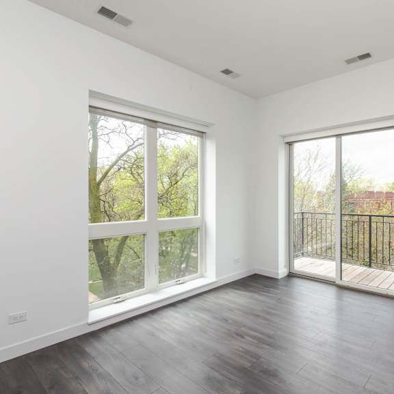 an empty living room with wood floors and large windows