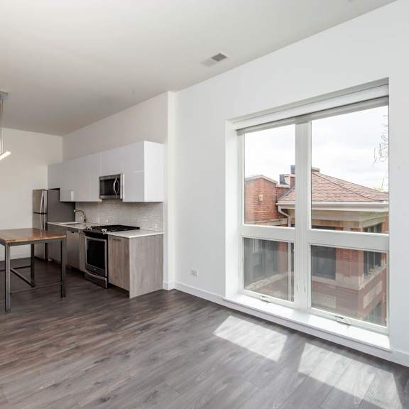 a living room with a large window and a kitchen