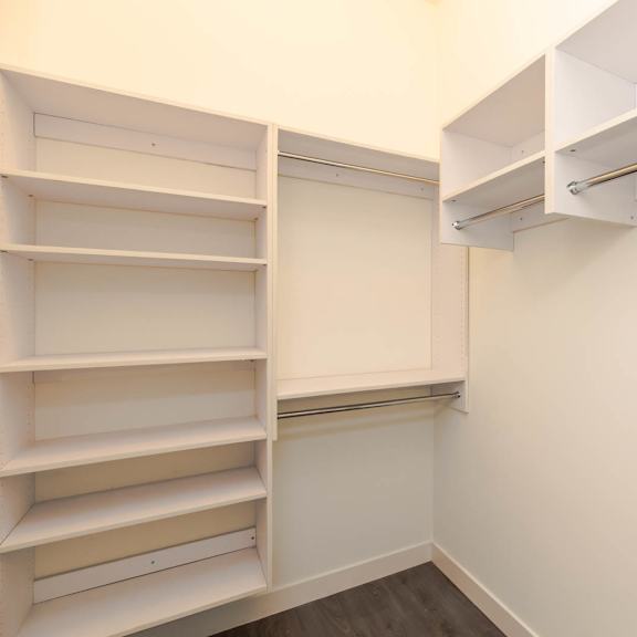 a walk in closet with white shelves and