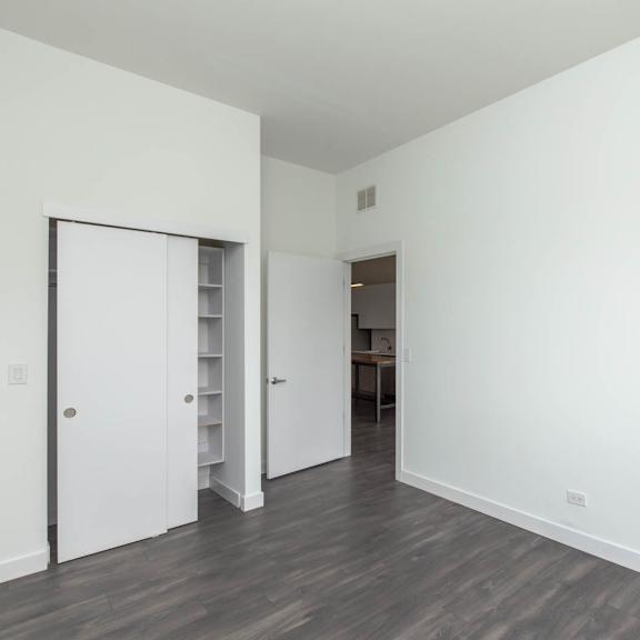 a bedroom with white walls and a door to a closet