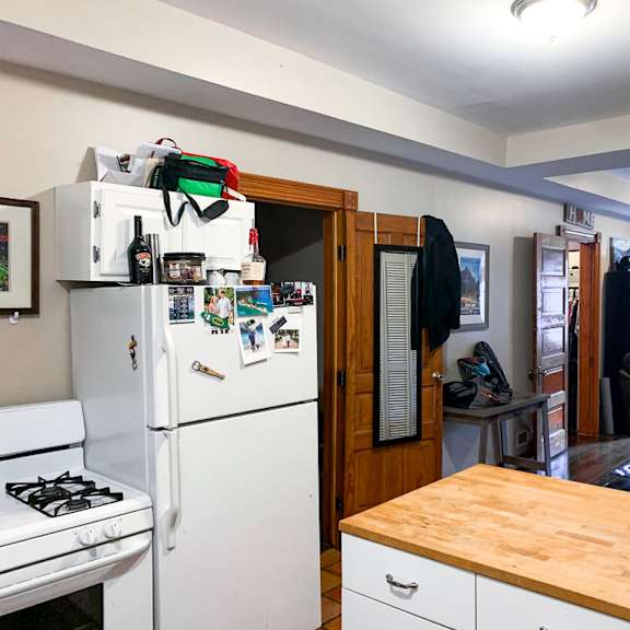 a small kitchen with a white fridge and a wooden table.