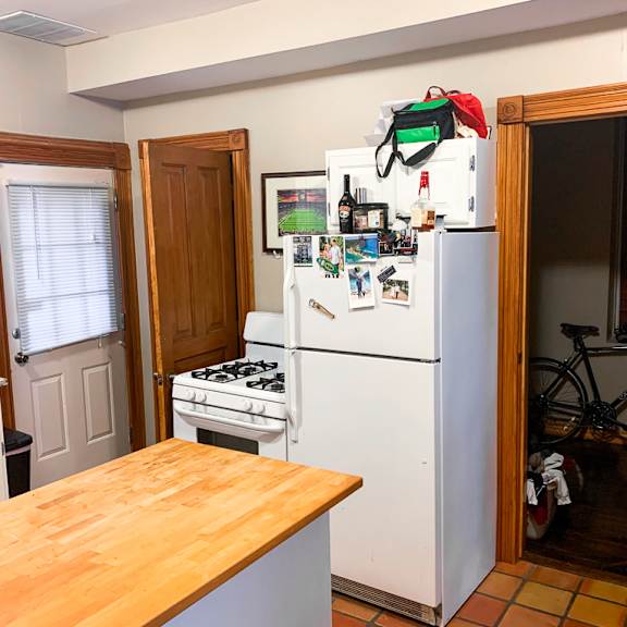 a kitchen with a white fridge and a wooden table.