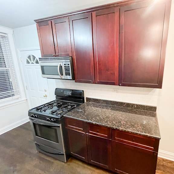 a kitchen with dark wood cabinets and a black stove top oven.