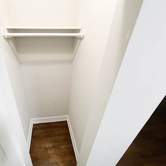 a white shelf in a white room with a wooden floor.