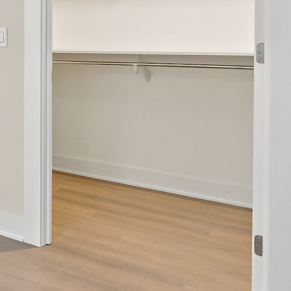 a white door is open to a room with a white ceiling and wooden floor.