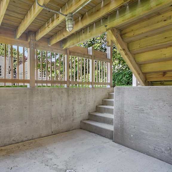 a wooden balcony with concrete stairs and walls.