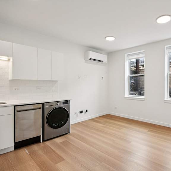 a clean, empty room with a washing machine and a window showing an outdoor view.