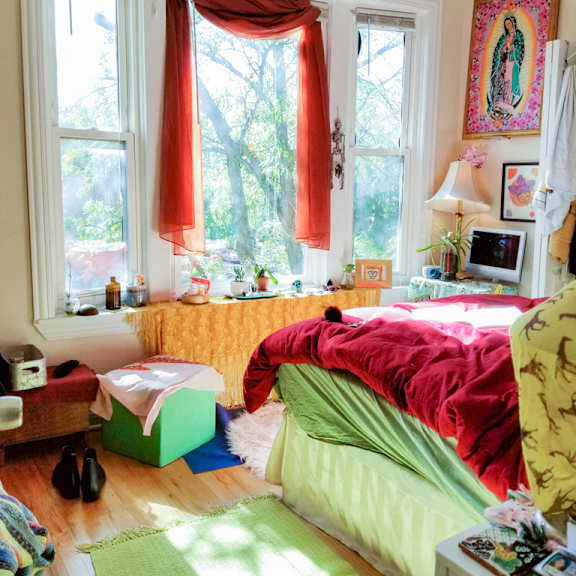 a bedroom with a bed and a window with red curtains