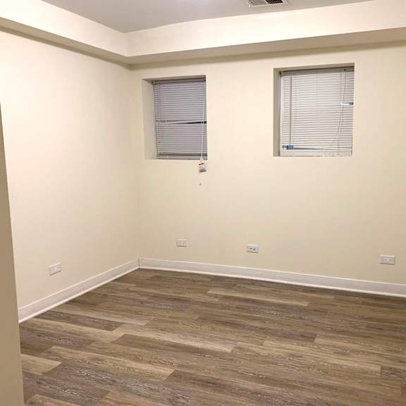 a room with wood flooring and two windows