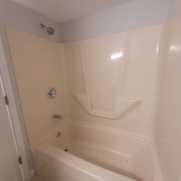 a white bathroom with a tub and a shower