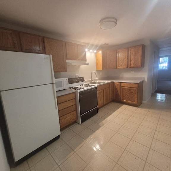 an empty kitchen with white appliances and wooden cabinets