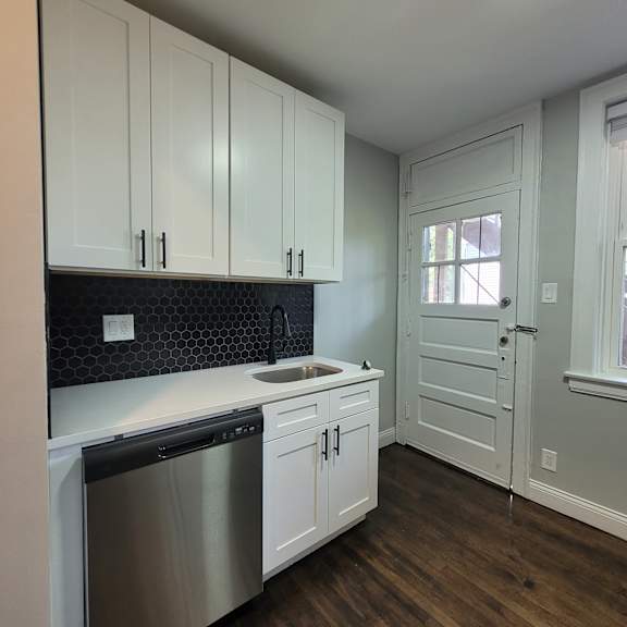 a kitchen with white cabinets and a black backsplash.