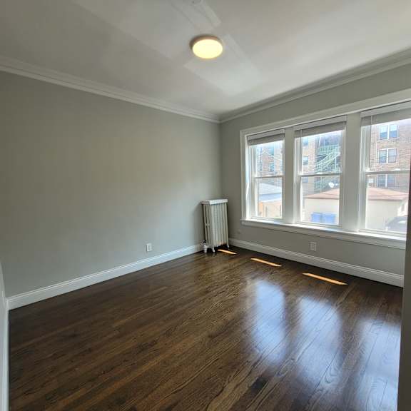 a room with wooden floors and a window overlooking a building.