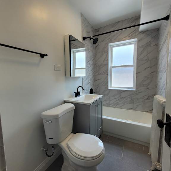 a white toilet with a white tank and a white sink in a bathroom.