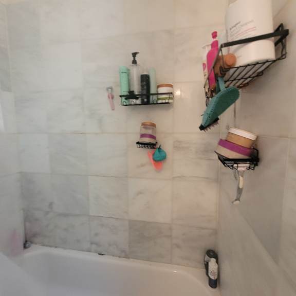a bathroom with a white tub and a shelf with toiletries.