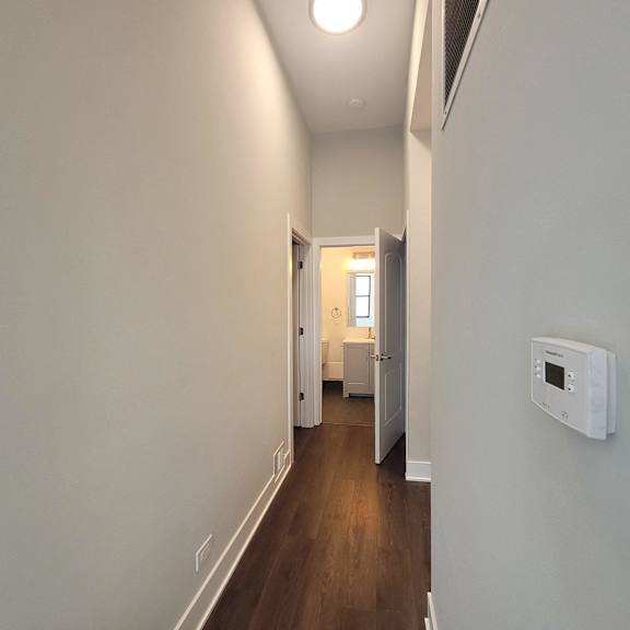 a hallway with a white wall and a door to a bathroom