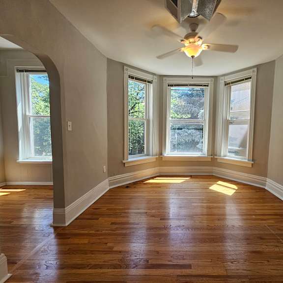 a room with a ceiling fan and wooden floors.