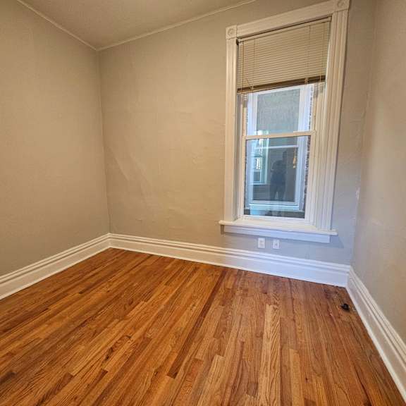 a room with wooden floors and a window with blinds.