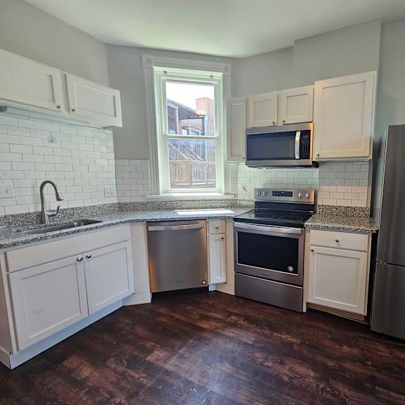 a kitchen with white cabinets and a stainless steel refrigerator.