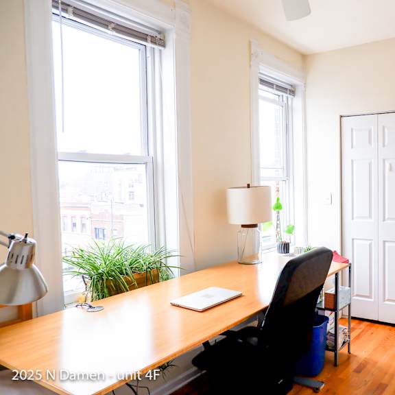 a room with a desk, chair, and a white door.