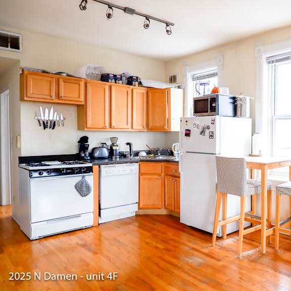 a kitchen with orange cabinets and white appliances.