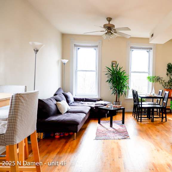a living room with a couch, chairs, and plants.